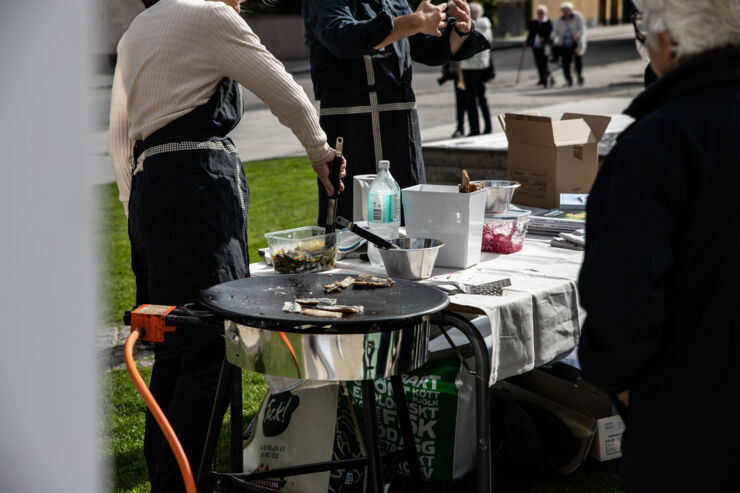 Närbild på personer som lagar mat utomhus.