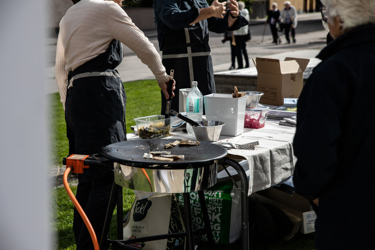 Närbild på personer som lagar mat utomhus.
